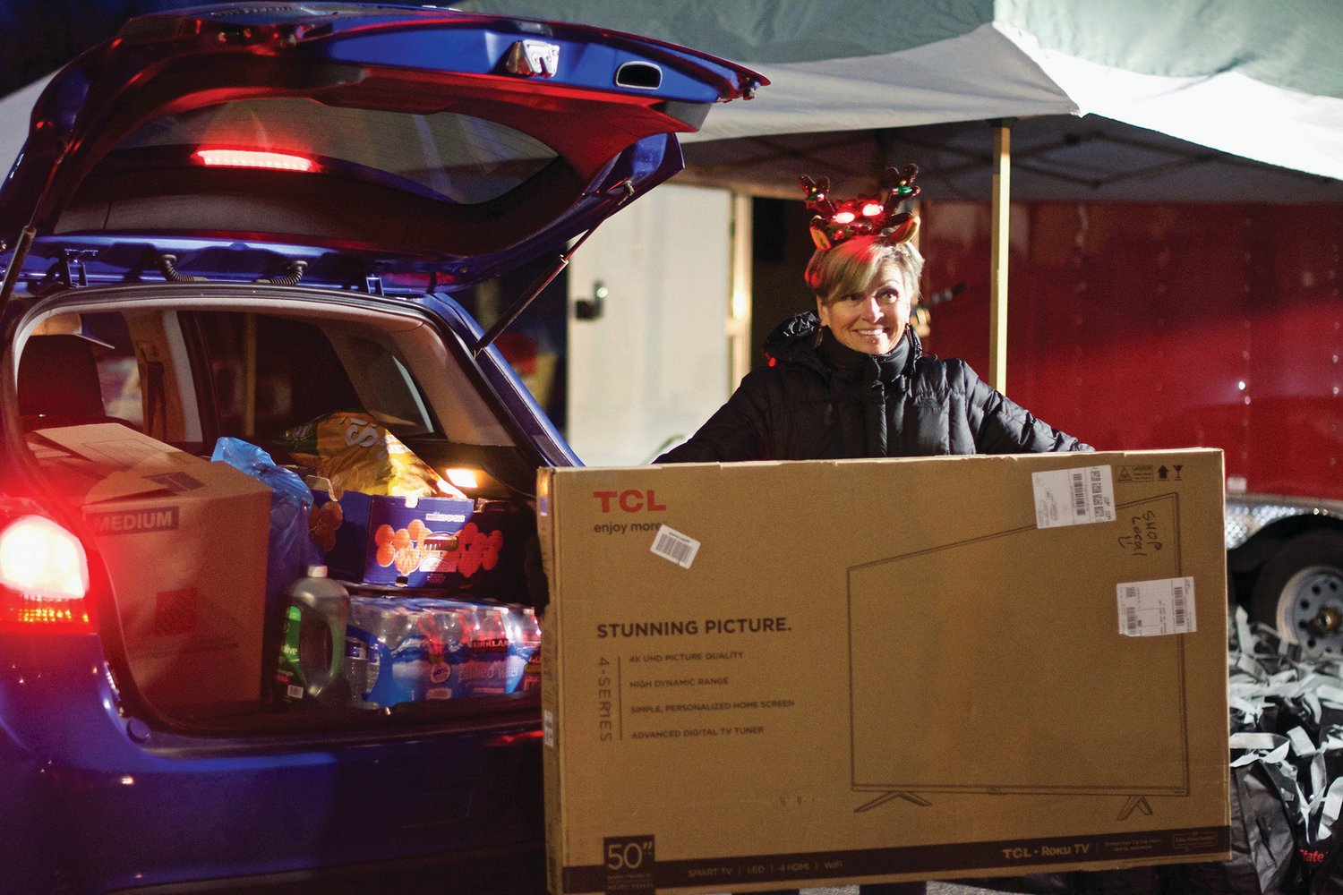 A woman holds up a TV before it is given away to the first car through the line at the Lewis County Mall Wednesday night for Centralia-Chehalis Chamber of Commerce’s “Choose Local Black Friday” event.